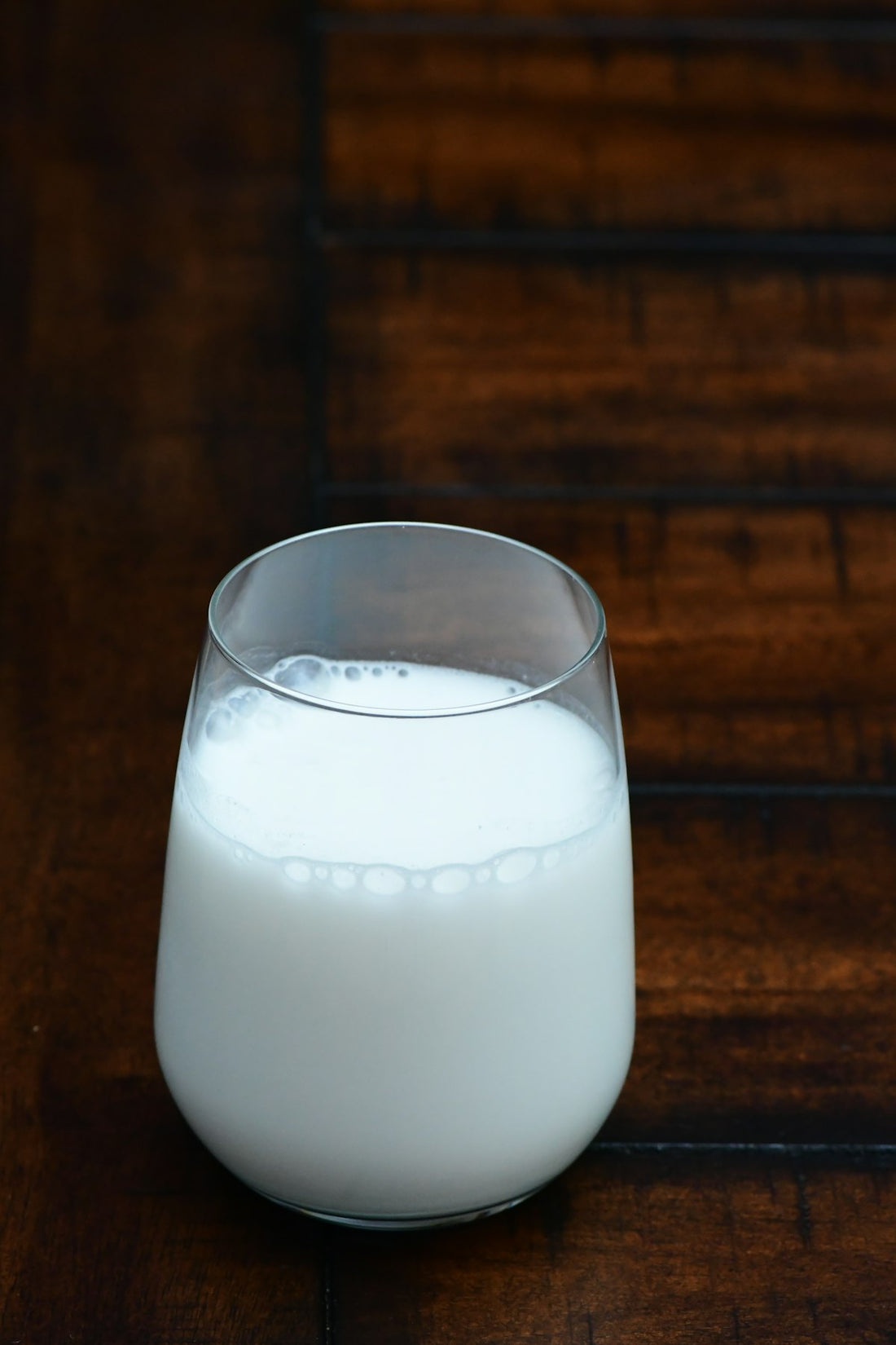 Glass of plant-based alpiste milk on a dark wooden table