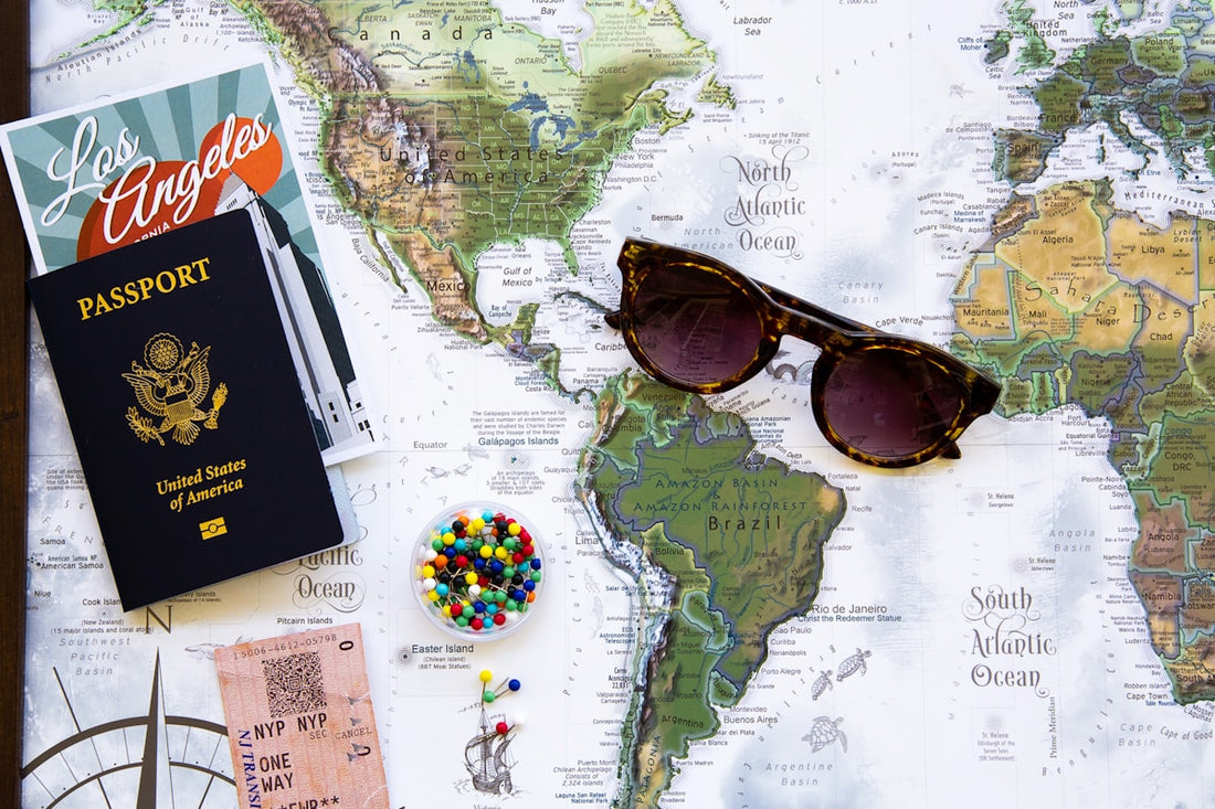 Passport, sunglasses, and world map flat lay for trip planning