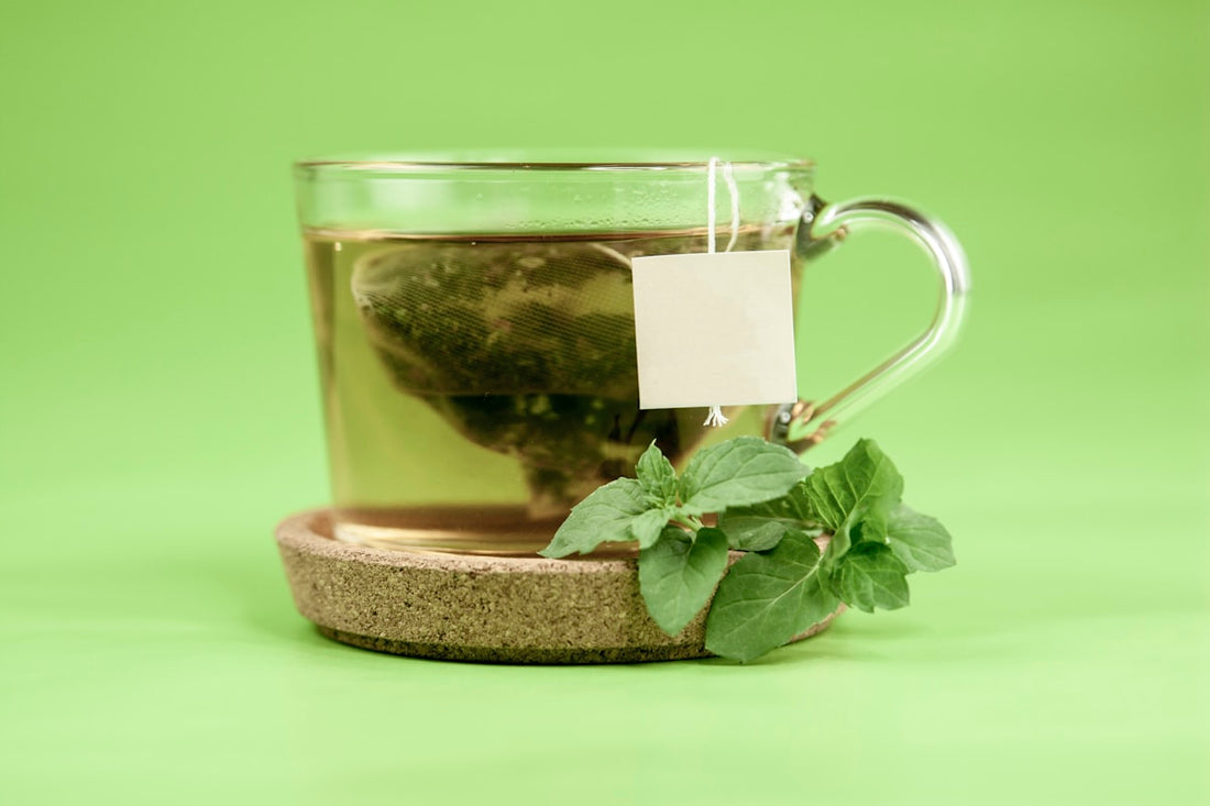 Clear glass mug of herbal tea with green leaves