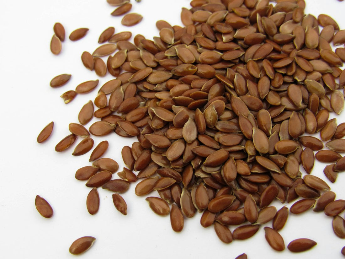 Close-up of brown whole flaxseeds (linaza) on a white surface